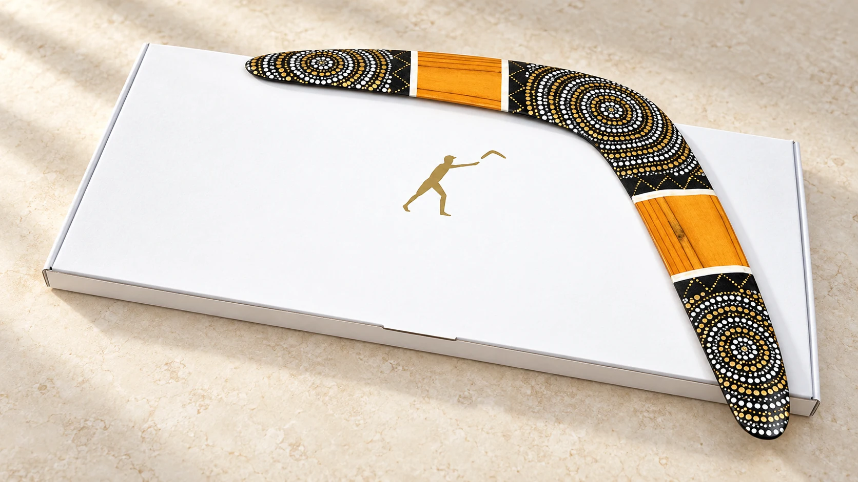Wooden boomerang on a white gift box Illustration of a Golden Sun wooden boomerang on a white gift box with a gold logo.