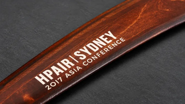 Engraving filled with white colour — illustration Illustration of white-filled HPAIR Sydney 2017 conference engraving on a wooden boomerang.
