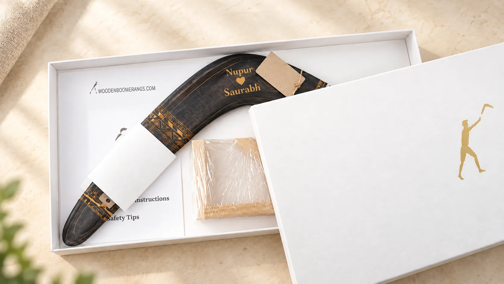 01-aztec-personalized-gift-box Illustration of a personalized dark Aztec boomerang with two names and a heart in a white gift box.