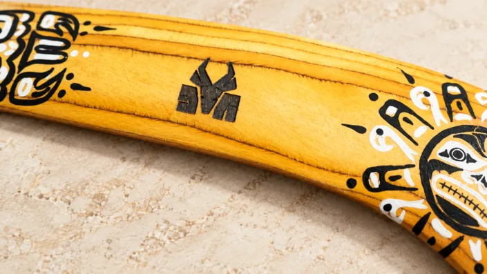 04-golden-custom-logo-detail Illustration of an engraved custom logo on a golden wooden boomerang with black and white artwork.