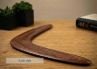 Back side of the handcrafted wooden boomerang showing natural wood grain on a table.