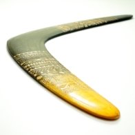 Angled close-up view of the wooden boomerang showing the aerodynamic airfoil and plywood layers.