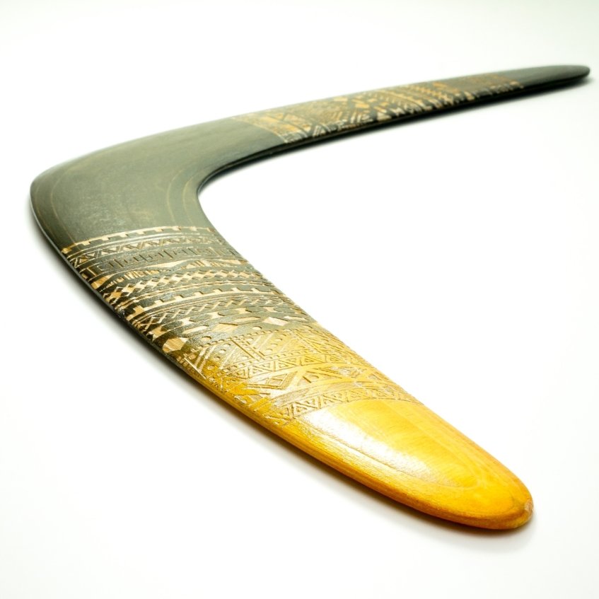 Angled close-up view of the wooden boomerang showing the aerodynamic airfoil and plywood layers.