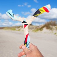 hurricane-boomerang-beach-activity Hand holding colorful Hurricane boomerang at the beach with clouds in background.