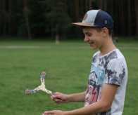 Smiling teenager holding a Seerblade wooden boomerang in a green park.