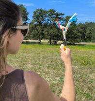 throwing-hurricane-boomerang-park-field Girl preparing to throw the Hurricane returning boomerang in a green park field.