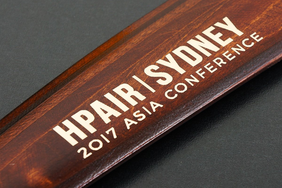 Dark stained wooden boomerang with laser-engraved text reading HPAIR Sydney 2017 Asia Conference