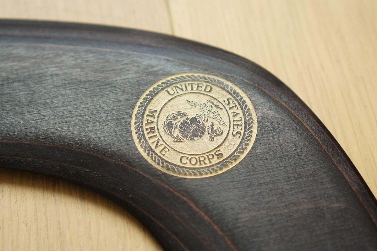 Dark stained wooden boomerang with laser-engraved United States Marine Corps seal in gold detail