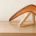 Simple care. Brown wooden boomerang displayed on a pale wooden stand indoors.